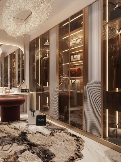 Our custom storage solutions combine elegance with practicality. This walk-in closet is designed for the private joys of dressing up, featuring mirrored and glass-fronted wardrobes with integrated lighting to display bags and accessories. A central vanity and plush seating create a functional and luxurious personal space.