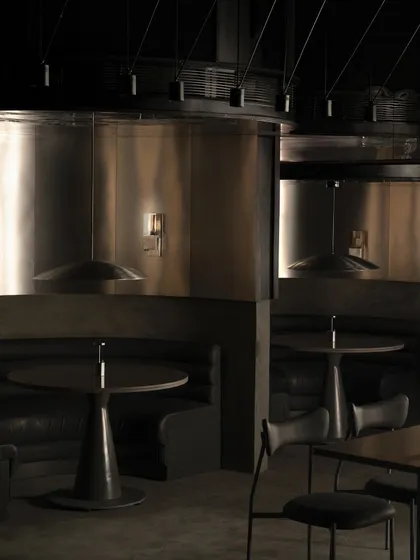 Another perspective of the dining area, highlighting the custom pendant lights and the reflective steel panels.