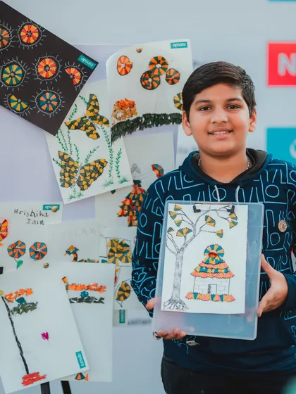 A young boy proudly displays his artwork made from pencil shavings. I love incorporating eco-friendly and recycled materials into my art workshops.