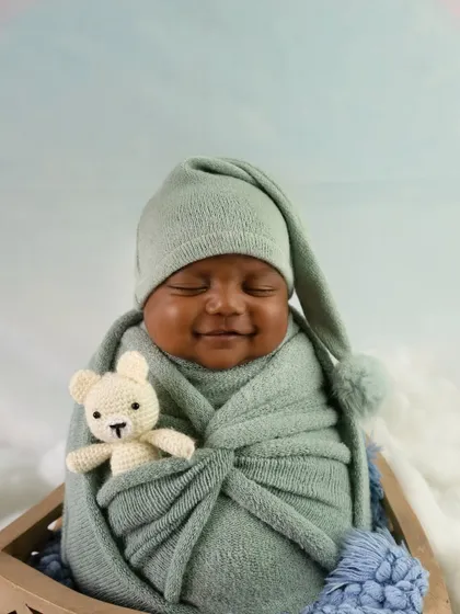 A precious moment captured as this newborn smiles while snuggled in a mint green wrap. I aim to catch these fleeting expressions that you will cherish forever.