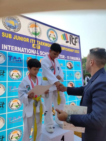 An official awards a certificate to our student on the podium at the Delhi State Championship.