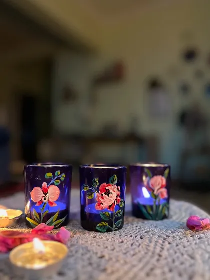 A set of deep blue candle holders painted with delicate sweet pea and rose designs.