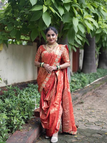 A full-length view of the orange Nauvari saree, showing its graceful drape against a natural backdrop.