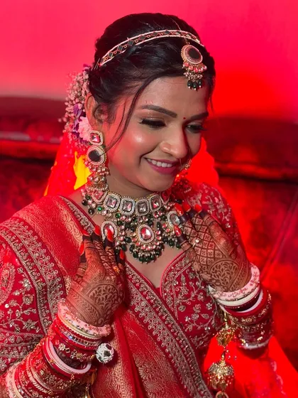 The bride adjusting her beautiful necklace, giving a great view of her intricate mehndi and flawless makeup.