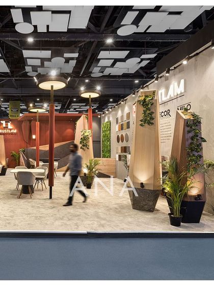 A visitor walks through the Trustlam '23 space, demonstrating the open and interactive nature of the design. The lamp-post sculptures are integrated with planters, adding a natural element to the abstract design.