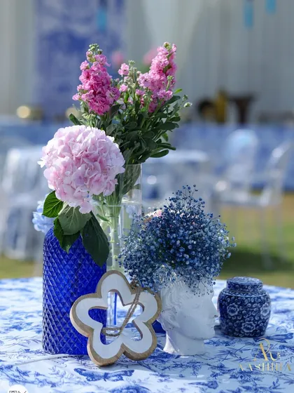A beautiful tabletop detail from the 'Azure Reverie' theme, featuring blue and white patterned pottery, cobalt blue vases, and a mix of pink and blue florals.