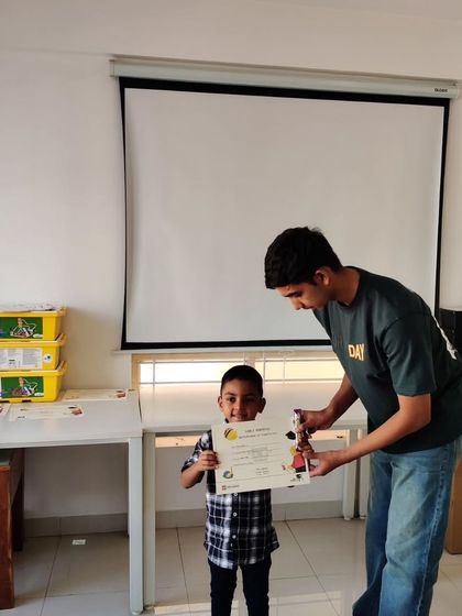 An instructor presents a student with his certificate and a LEGO trophy, recognizing his hard work and achievement.