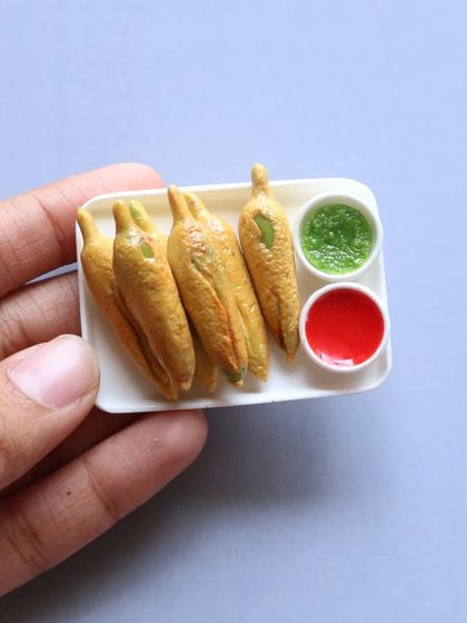 A plate of crispy mirchi bajji (chili fritters) with green and red chutney, a spicy and delicious snack.