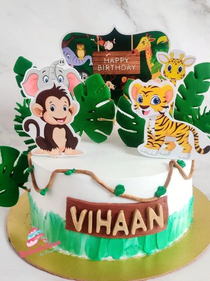 A fun jungle theme cake for Vihaan's birthday. This cake uses cute animal toppers and handcrafted tropical leaves to create a wild party atmosphere.