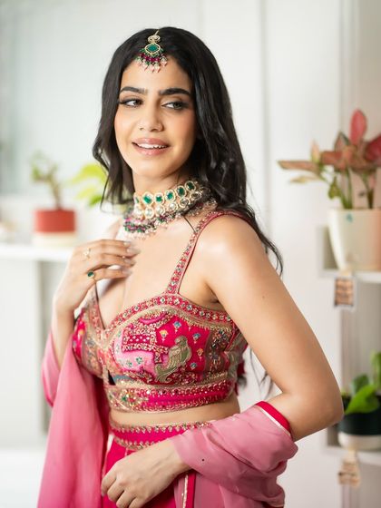 A close-up on the detailed blouse and jewellery. The maang tikka completes this traditional look.