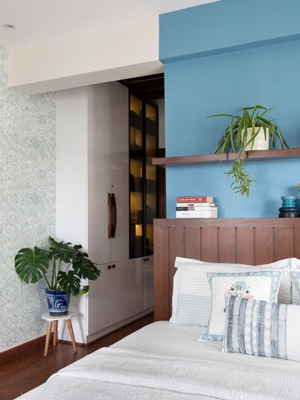 A wider view of the master bedroom, showing how the blue feature wall and wooden headboard connect with the walk-in closet area, which is subtly visible.