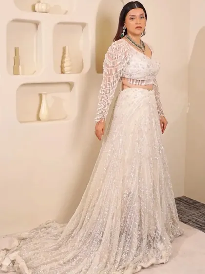 For the modern bride who dreams in white. This elegant pearl and sequin lehenga with a dramatic trail is perfect for a reception or engagement, proving that bridal glam comes in every color.