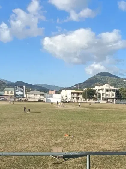 A wide shot of a match in progress in Trinidad, with mountains in the background.