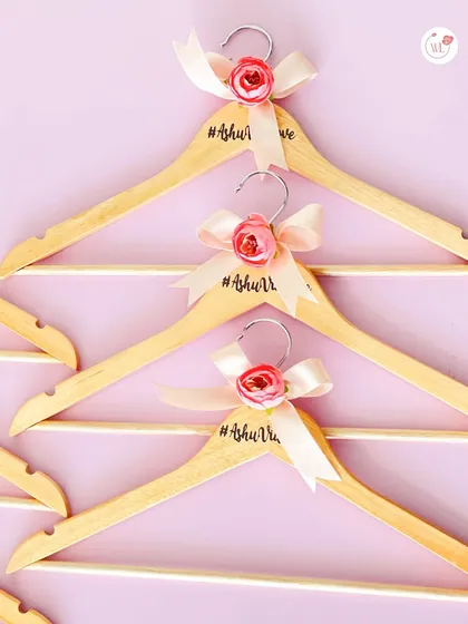 Personalized wooden hangers with the couple's wedding hashtag, decorated with a small rose and ribbon. A perfect detail for wedding day photos.