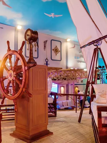 A view of the captain's deck from the nautical-themed party. It features a ship's wheel and a telescope, providing a fun and interactive photo opportunity for guests.