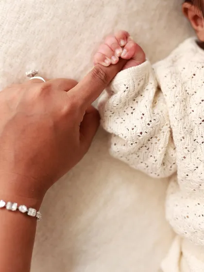 A newborn's tiny hand grips their mother's finger. A simple, powerful image of trust and connection.