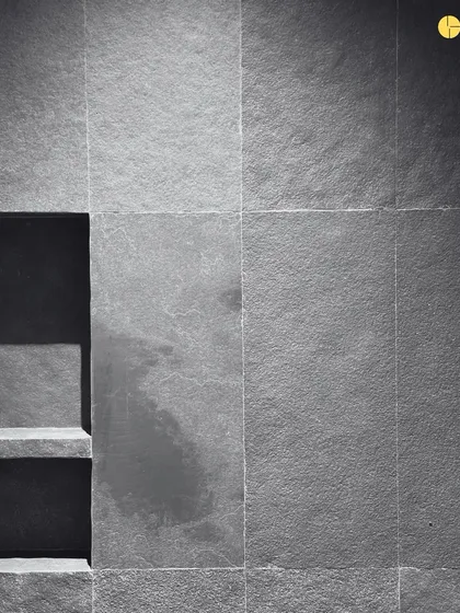 A detail of a stone-clad wall with a built-in niche. The rough texture of the stone adds a tactile quality to the space, turning a simple wall into a sensory experience.