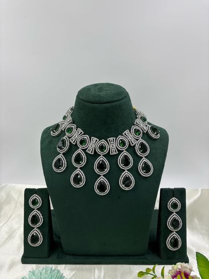A modern necklace set with large, teardrop-shaped stones in a cascading design. This piece is available in several colors, including pink, green, and red, offering a bold and stylish look.