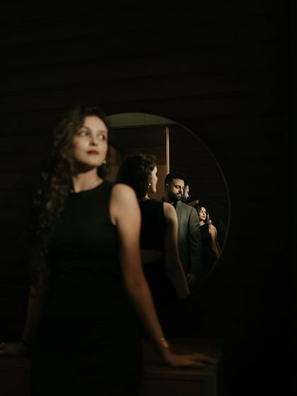 An artistic and conceptual portrait using a mirror to create layers of reflection. This dramatic, low-light shot plays with focus and perspective to tell a complex visual story.