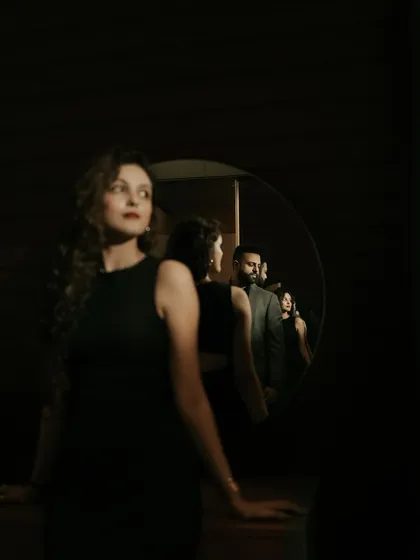 An artistic and conceptual portrait using a mirror to create layers of reflection. This dramatic, low-light shot plays with focus and perspective to tell a complex visual story.