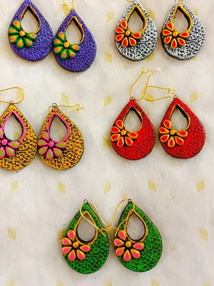 These teardrop-shaped danglers have a lovely textured finish and a small, 3D flower in the center. They are available in many colors, including purple, white, yellow, red, and green.