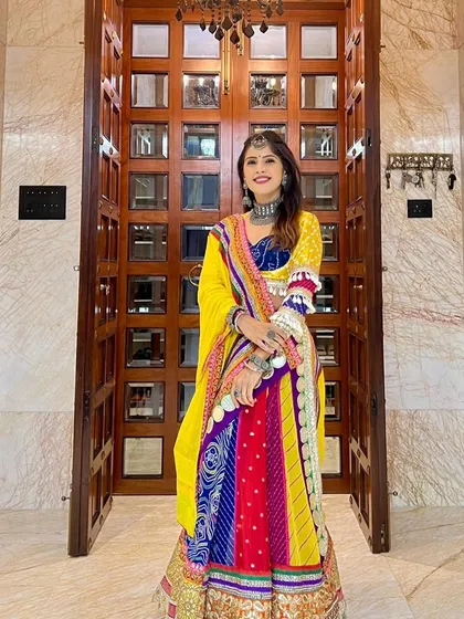 Our client is ready for the festivities in her vibrant, multi-colored lehenga. The combination of yellow, blue, and red with traditional patterns makes this a standout piece for Navratri or a Sangeet night.