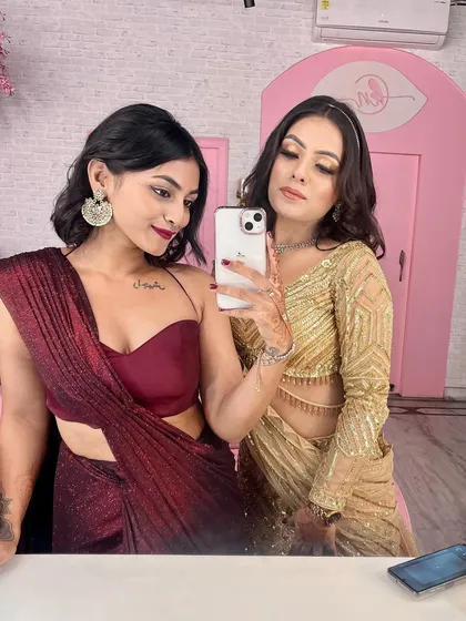 A fun mirror selfie with a friend, showing off our contrasting wedding outfits. My simple maroon gown and her glittering gold ensemble complement each other perfectly.