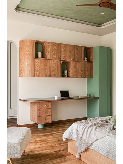 The custom-designed study unit in the girl's bedroom features curved floating oak cabinetry with arched niches. The design is functional, providing ample storage and desk space, while maintaining a soft and playful aesthetic.