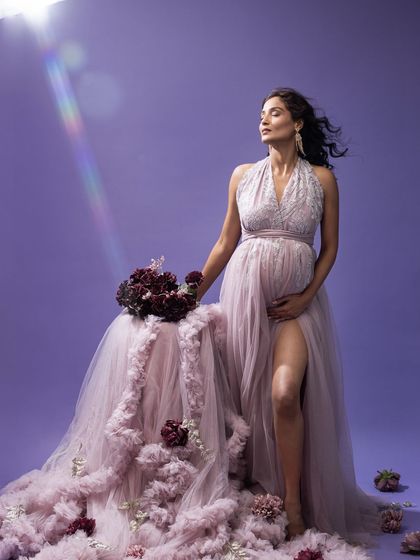 A vision as dreamy as stardust. The lilac dress and matching backdrop, softly lit, create a stunning, ethereal atmosphere for this maternity portrait.