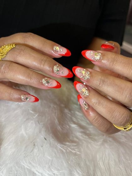 Go bold with this glamorous red and gold set. It features a vibrant red French tip on a sheer base, with accent nails completely covered in chunky gold rhinestones for maximum impact.