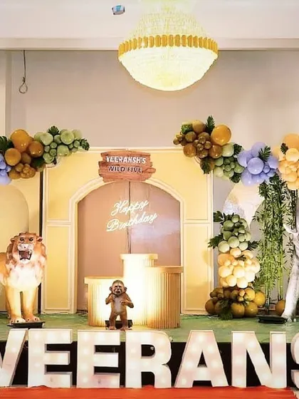 Welcome to the jungle. This 'Wild One' birthday theme features large 3D animal props, including a lion and elephant, set against a backdrop with the birthday boy's name in lights.