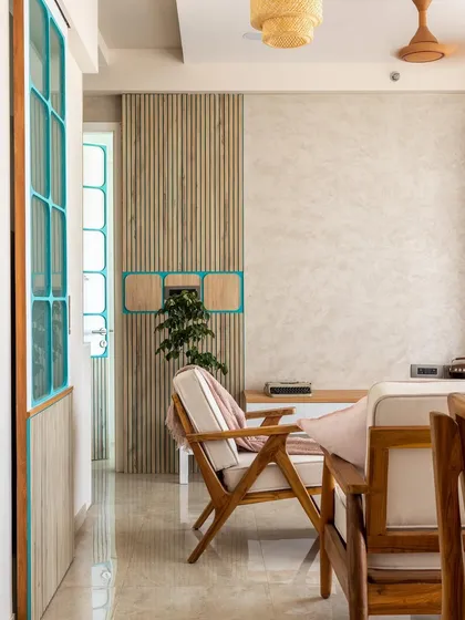 The subtle play of light and color is key. The teal-framed doors with chequered patterns and wooden louvers bring a unique personality to this Japandi-inspired living space.