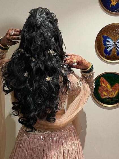 A detailed shot of a beautiful hairstyle for a reception or sangeet. The soft curls are gathered into an elegant half-up style.