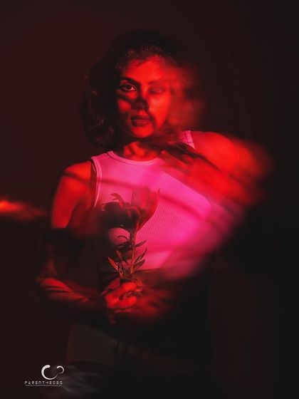 A moment of clarity amidst the blur. Her face comes into partial focus, creating a powerful contrast between stillness and movement in this experimental red-light portrait.