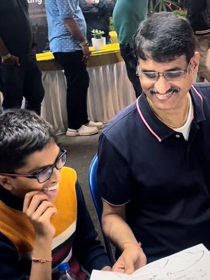 Sharing a laugh over a finished sketch. This is a typical scene at my caricature station, where guests gather to watch the fun unfold.