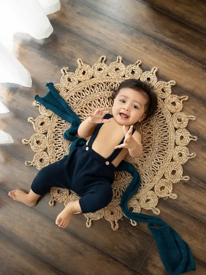 An overhead shot of a happy baby in a cute outfit, lying on a textured rug. This perspective offers a fun and unique view of your little one.