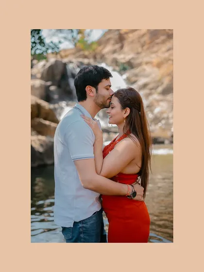 A classic romantic forehead kiss, beautifully framed against the natural backdrop of a waterfall.