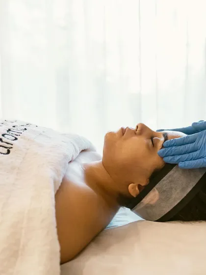 Revitalize your skin and rejuvenate your spirit. This client is enjoying a moment of tranquility during a facial, wrapped in a comfortable robe embroidered with my brand.