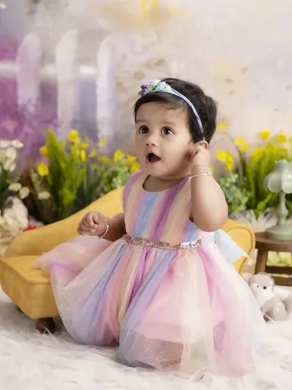 A rainbow of colors for a beautiful little girl. Her pastel rainbow dress looks stunning against the soft, painterly flowers of our garden-themed backdrop.