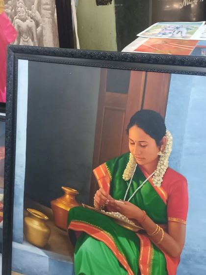 A beautiful, realistic portrait of a woman in a green saree, framed and displayed at the Chithrasanthe art fair.