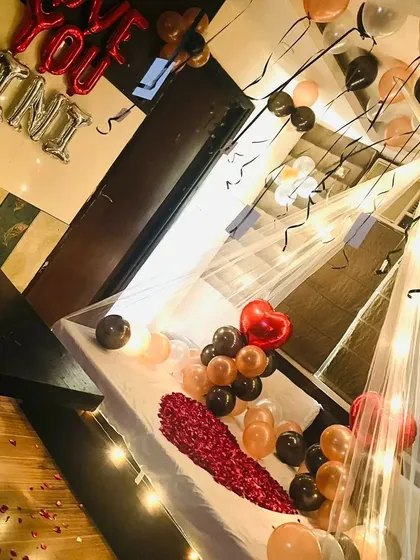 A stylish canopy decoration with rose gold and black balloons. This is a chic and modern color palette for a sophisticated romantic surprise.