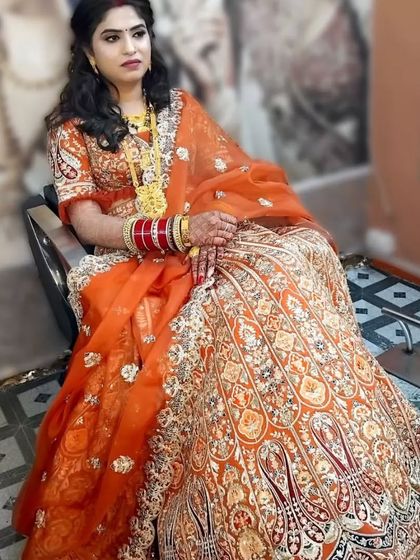 Another angle of this beautiful bride in her orange reception lehenga. The complete look, from makeup to hair, is designed to be elegant and photogenic.