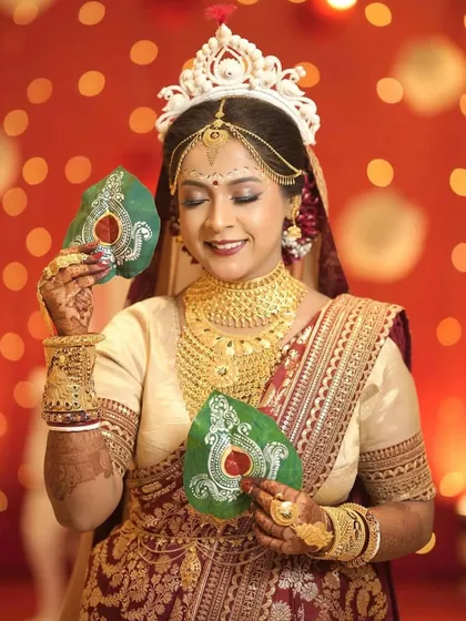 This bride is all smiles, holding her custom-painted paan leaves against a beautiful bokeh background. It's a perfect blend of tradition and personal style.