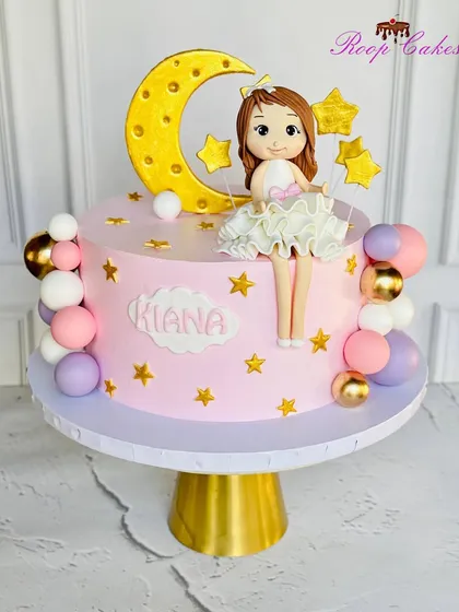 Under the moon, a little star shines bright. This cake features a sweet doll sitting on a crescent moon, surrounded by stars and colorful spheres.