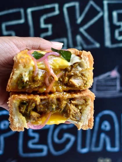 A cross-section of our Mutton Pepper Fry Puff Pie. The rich, spicy mutton filling contrasts perfectly with the thousands of flaky layers of our puff pastry.