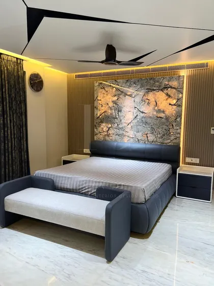 A bedroom should be a sanctuary. Here, we combined a custom leatherette bed with a dramatic, backlit marble-finish headboard and fluted wall panels. The geometric ceiling design with integrated lighting adds another layer of modern luxury.