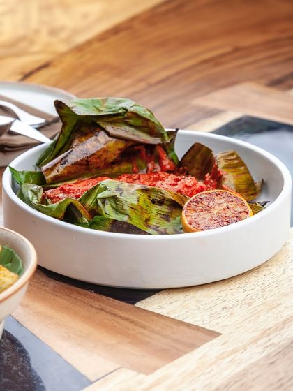 Bhetki fish marinated in a fiery red masala, wrapped in a banana leaf and steamed. The leaf imparts a subtle, earthy aroma to the tender fish.