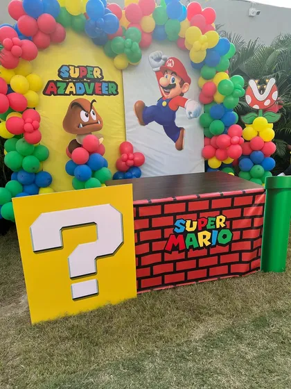 A detailed Super Mario backdrop with a classic question mark block and brick-themed cake table.