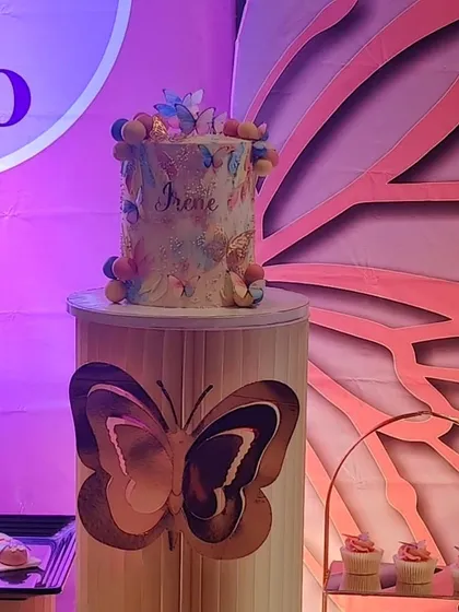 The butterfly-themed cake on a matching pedestal, creating a perfect centerpiece for the party.