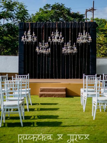 A shot of the stunning sangeet or reception stage decor, featuring elegant chandeliers against a dark backdrop.